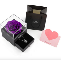Purple rose in a clear box with a necklace and card on a white background