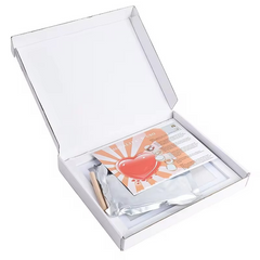 Open white box containing a card with a heart design and a small item on a white background