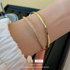 Gold-tone Celeste open cuff bracelets worn on a wrist