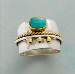 Silver ring with turquoise stone and gold accents on a gray background