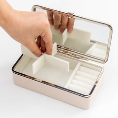 Jewelry box with a hand placing jewelry inside on a white background