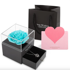Black gift box with turquoise rose, silver necklace, and pink heart card on a white background