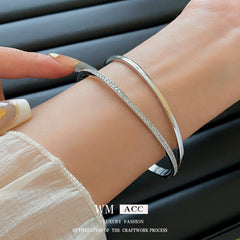 Silver-tone Celeste open cuff bracelets worn on a wrist