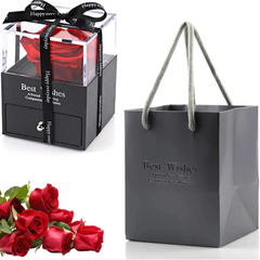 Gray gift bag with 'Best Wishes' text, red roses, and a clear box with a red rose inside on a white background.