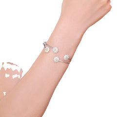 Silver bracelet with daisy flowers on a wrist against a white background