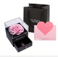 Pink rose in a box with 'Eternal Love' text, black gift bag, and pink heart-shaped card on a white background.