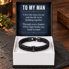 Personalized black braided name bracelet in an open gift box with a navy To My Man message card on a walnut and slate background